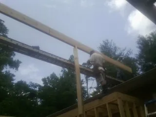 Carpenter setting a ridge beam over a new addition frame — Ice Dam Removal by Roofing Brothers in Saint Stephen