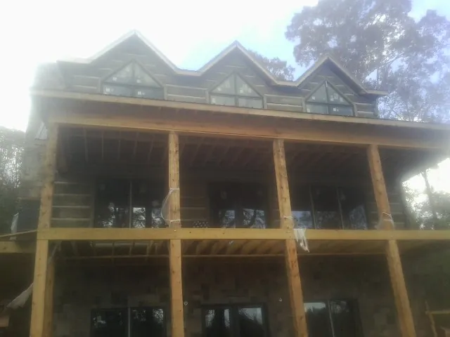 Dormers and porch framing on a large log home under construction — Roof Coating work by our crew in Saint Stephen