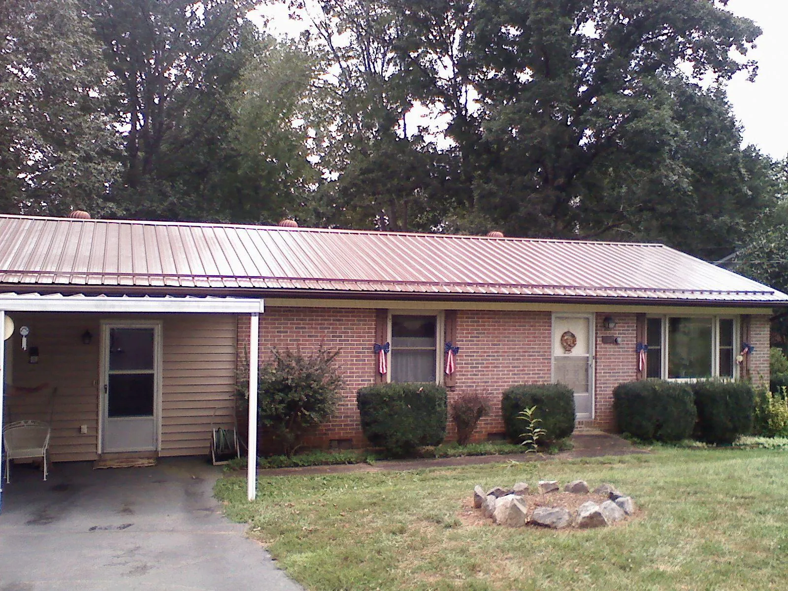 Bronze metal roof and carport on a brick ranch home — Roof Repair work by our crew in Saint Stephen