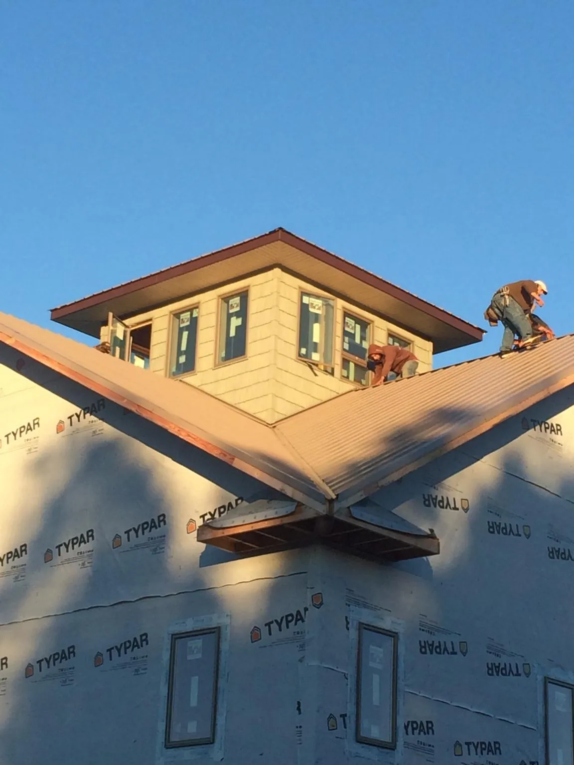 Roofers working around a rooftop cupola on a new metal roof at sunset — Roof Waterproofing in Saint Stephen by Roofing Brothers